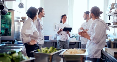 a group of five caterers standing in a circle planning for the day's work