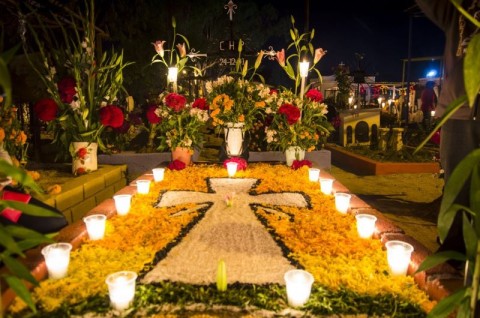a cross made of flowers surrounded by candles
