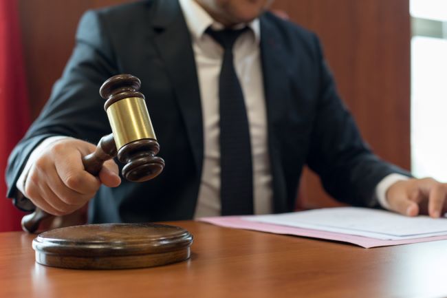 a man in a suit sitting at a desk while they hold a gavel